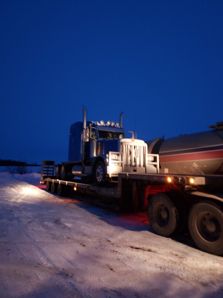 trailer hauling a blue truck cab